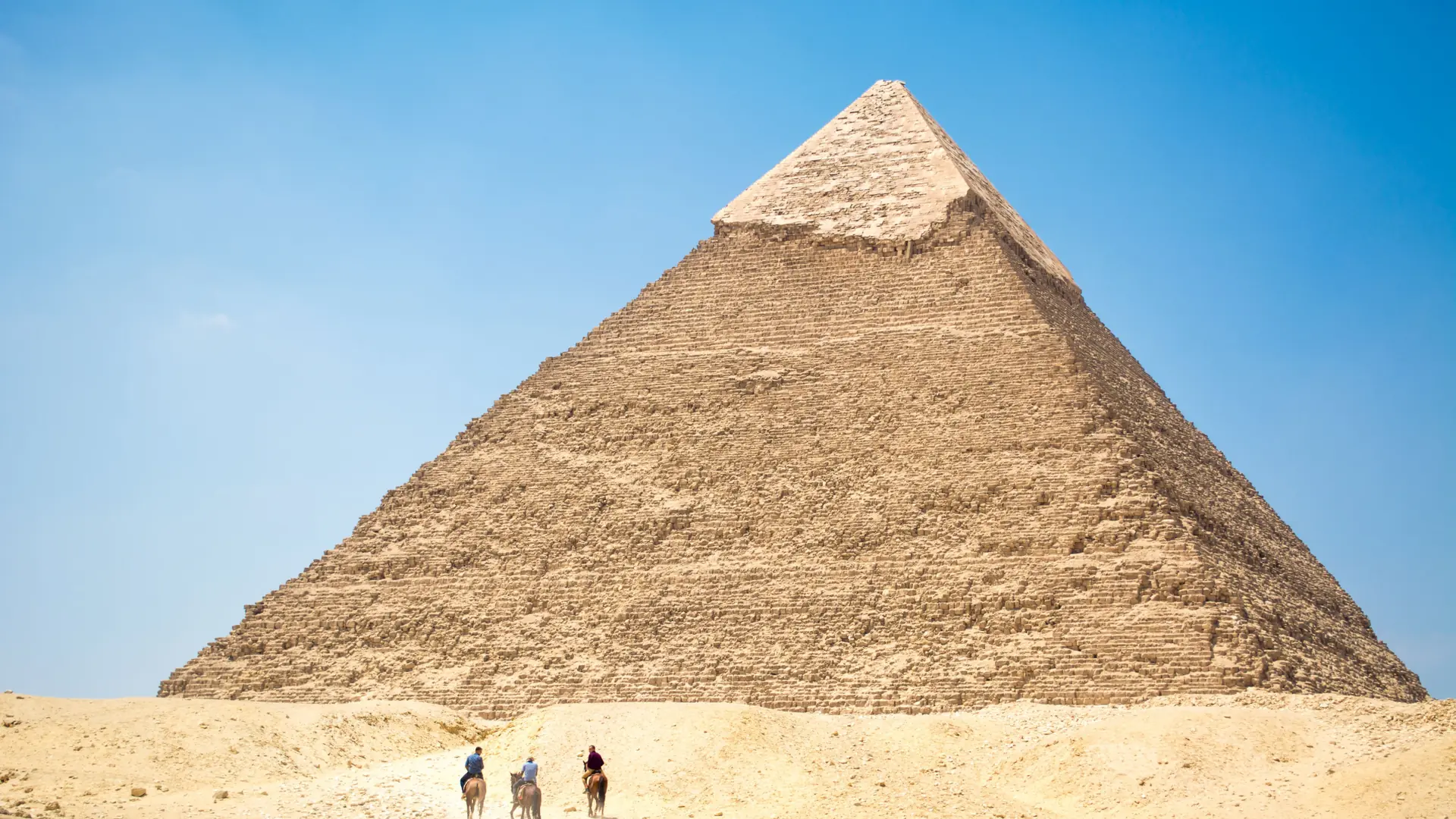 Sunlit pyramid rising above visitors on the Giza Plateau