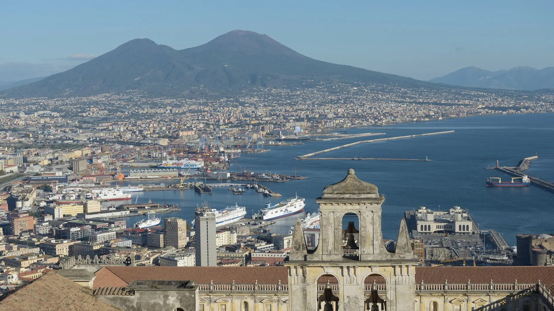 sunny Vomero hillside street with panoramic bay view and pastel Naples buildings