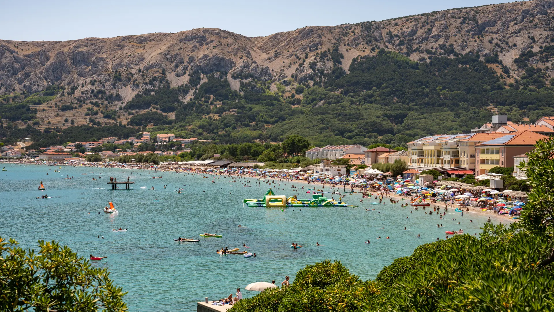 A relaxed Croatian Adriatic beach with shallow clear water and families in summer