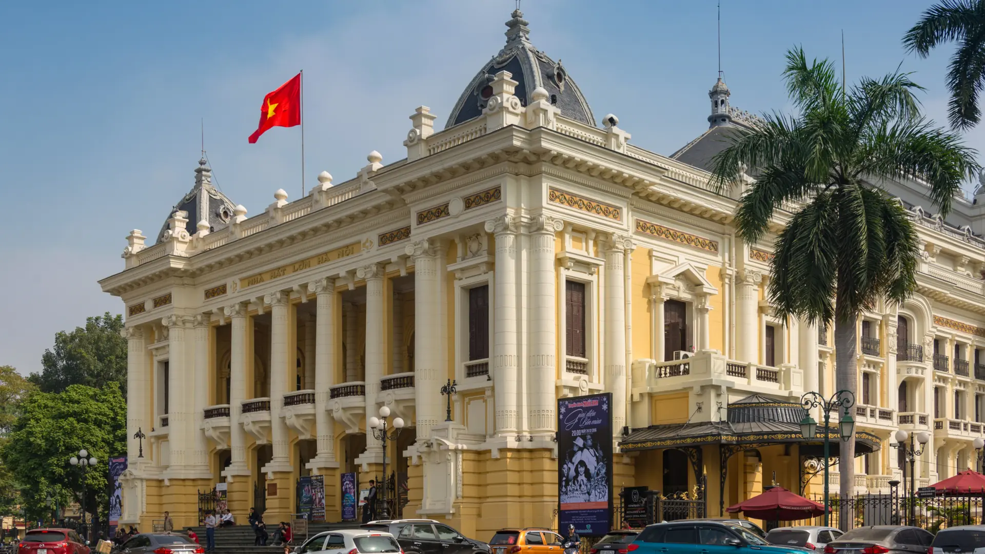 Hanoi Opera House with its yellow facade and white columns beneath a blue sky.