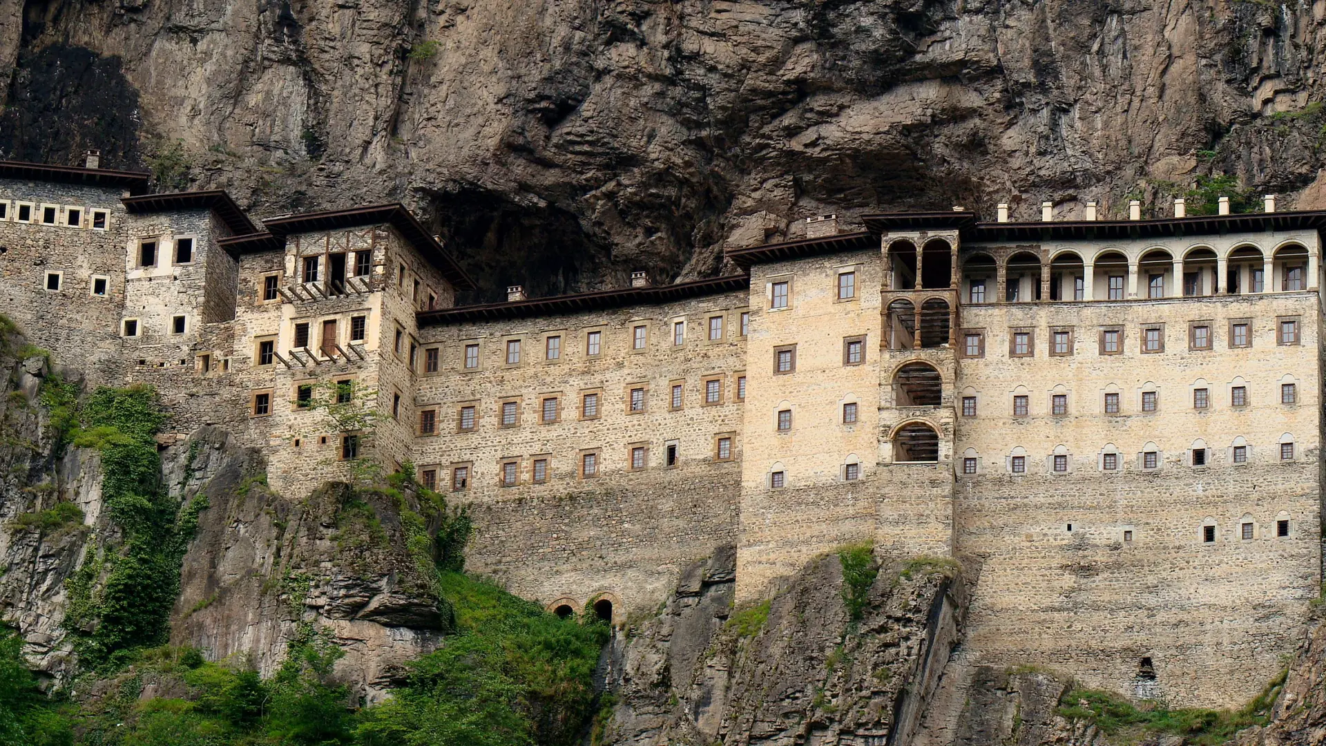 Sunlit stone façade of Sümela Monastery built into a sheer rock face above the Altındere valley