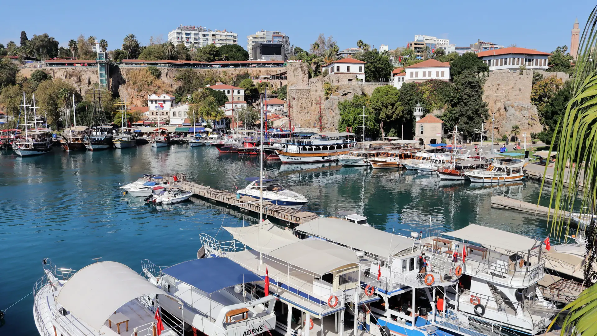 Boats in Antalya’s old harbour below Kaleiçi houses in sunshine