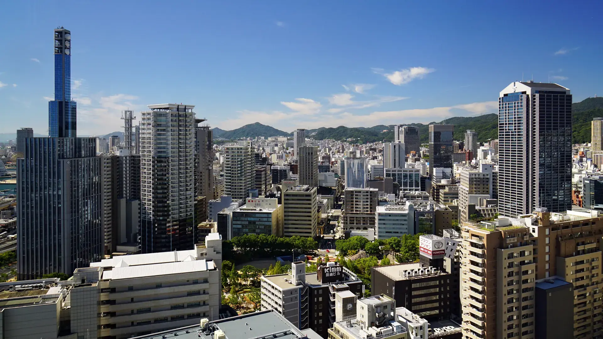 bright Sannomiya city centre with pedestrians, modern towers and mountain slopes