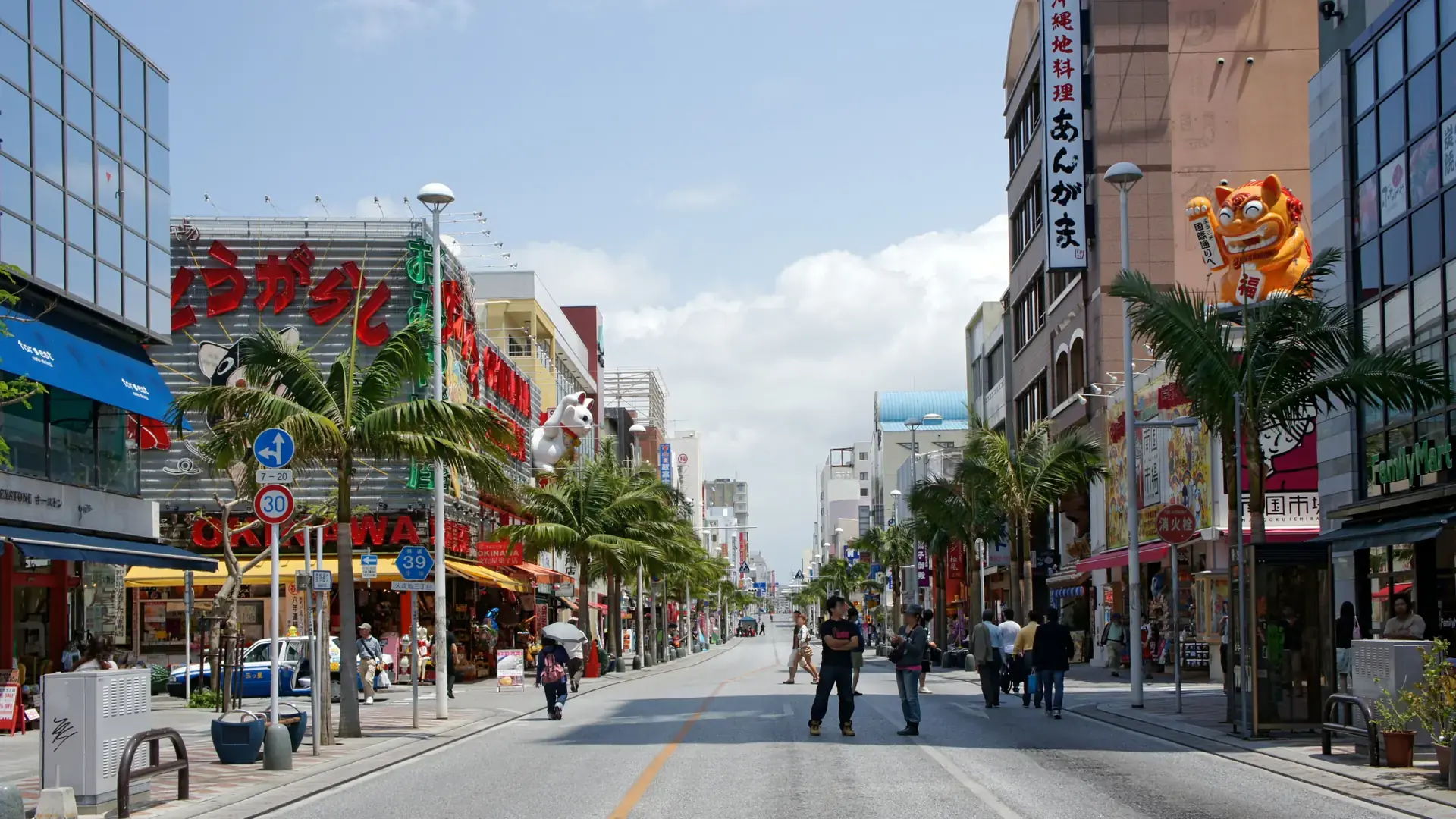 sunlit Kokusai-dori lined with palms, colourful signs and Naha pedestrians