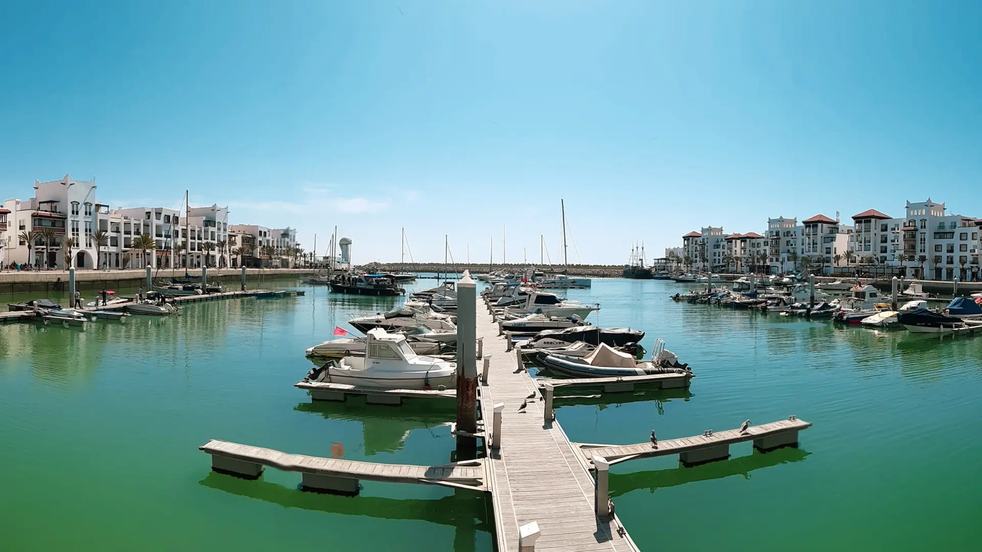 Boats moored around Agadir Marina beneath a clear blue sky