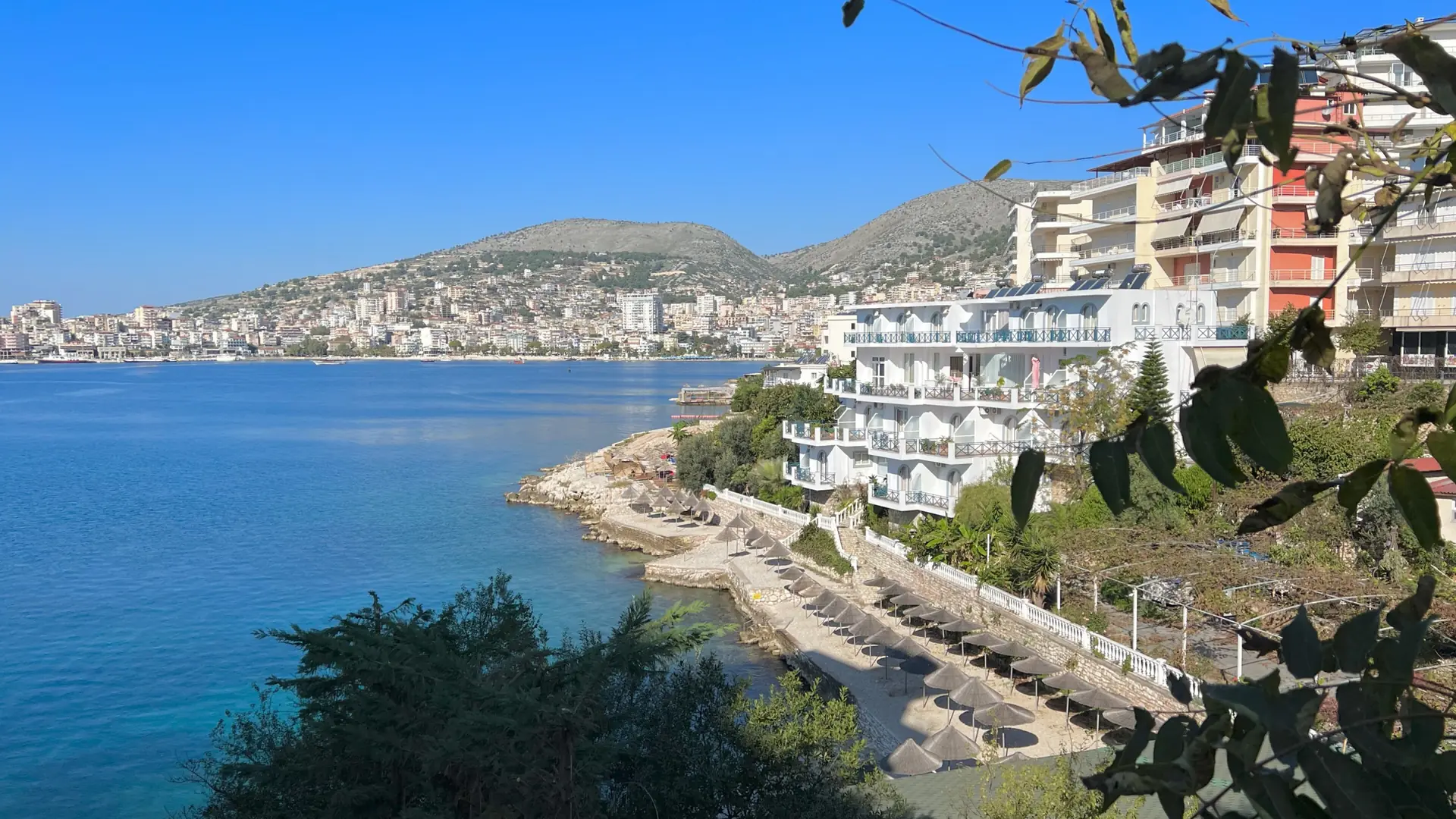 Sarandë's seafront hotels curving around the blue bay on a sunny day