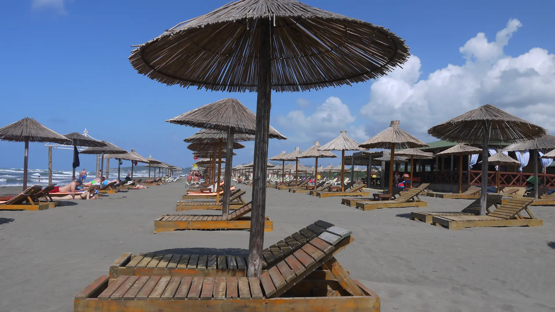 Sunlit straw parasols and loungers on mainland Imperial Beach, Velika Plaža, near Ada Bojana; this is not the island FKK resort