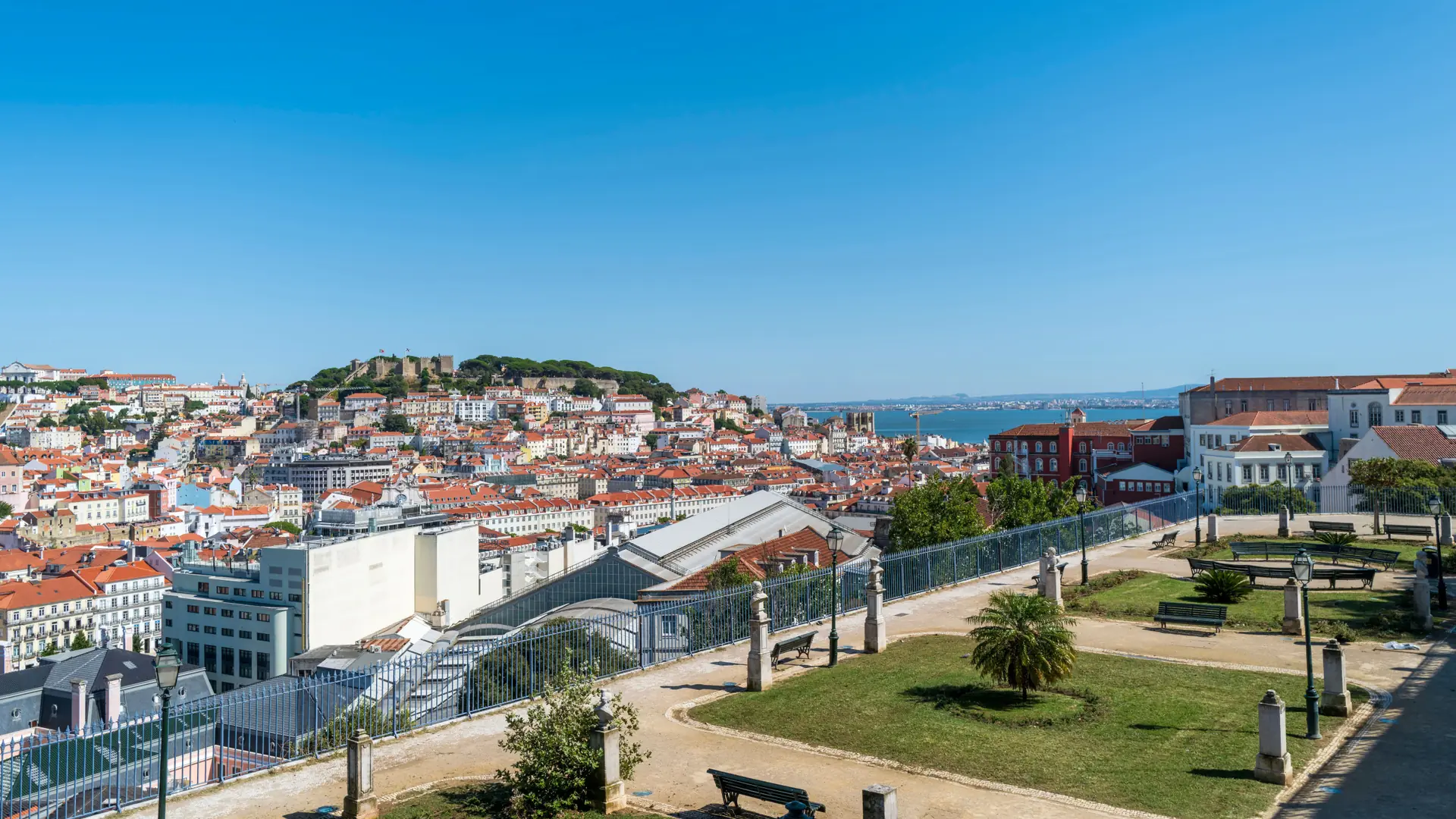 Lisbon rooftops and São Jorge Castle viewed across the garden at São Pedro de Alcântara
