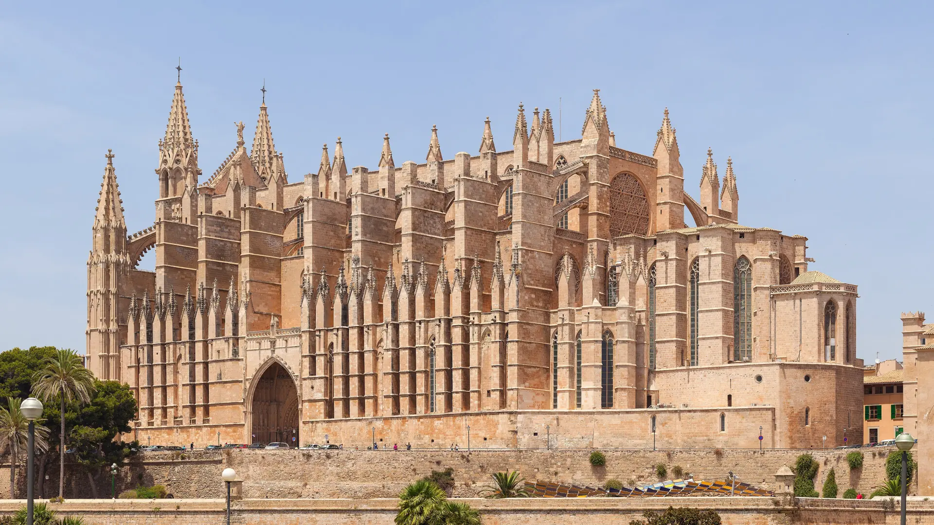Palma Cathedral's Gothic facade and spires rising above the old city walls under a clear blue sky