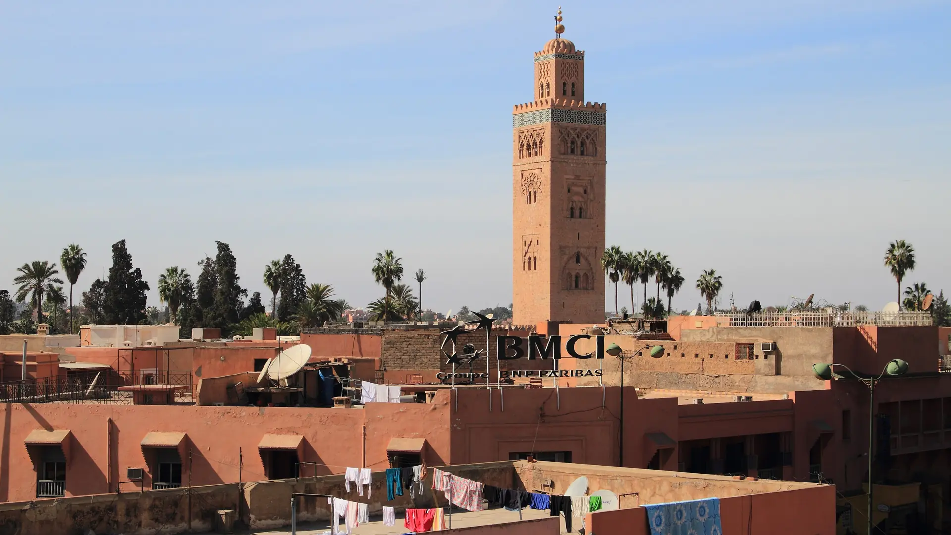 Koutoubia minaret above ochre Marrakech rooftops in daylight