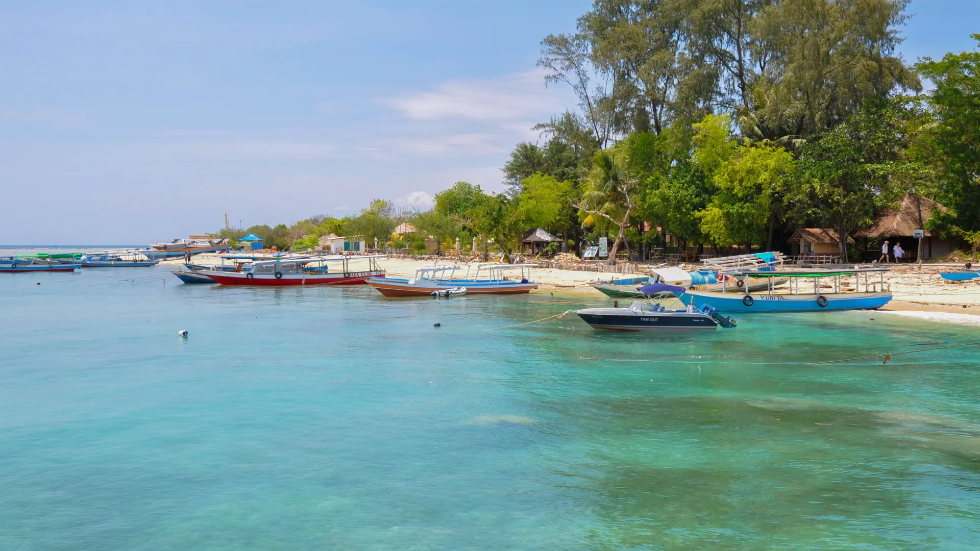Colourful boats moored in clear turquoise water beside Gili Trawangan’s shore