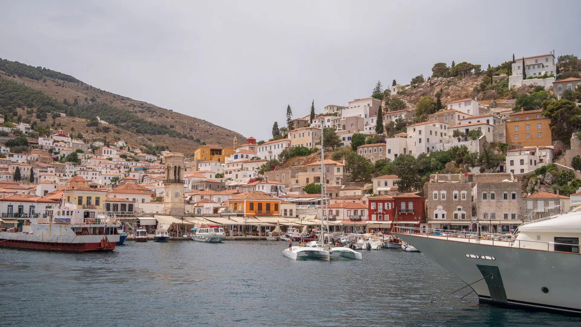 Hydra harbour framed by stone houses, red roofs and moored boats