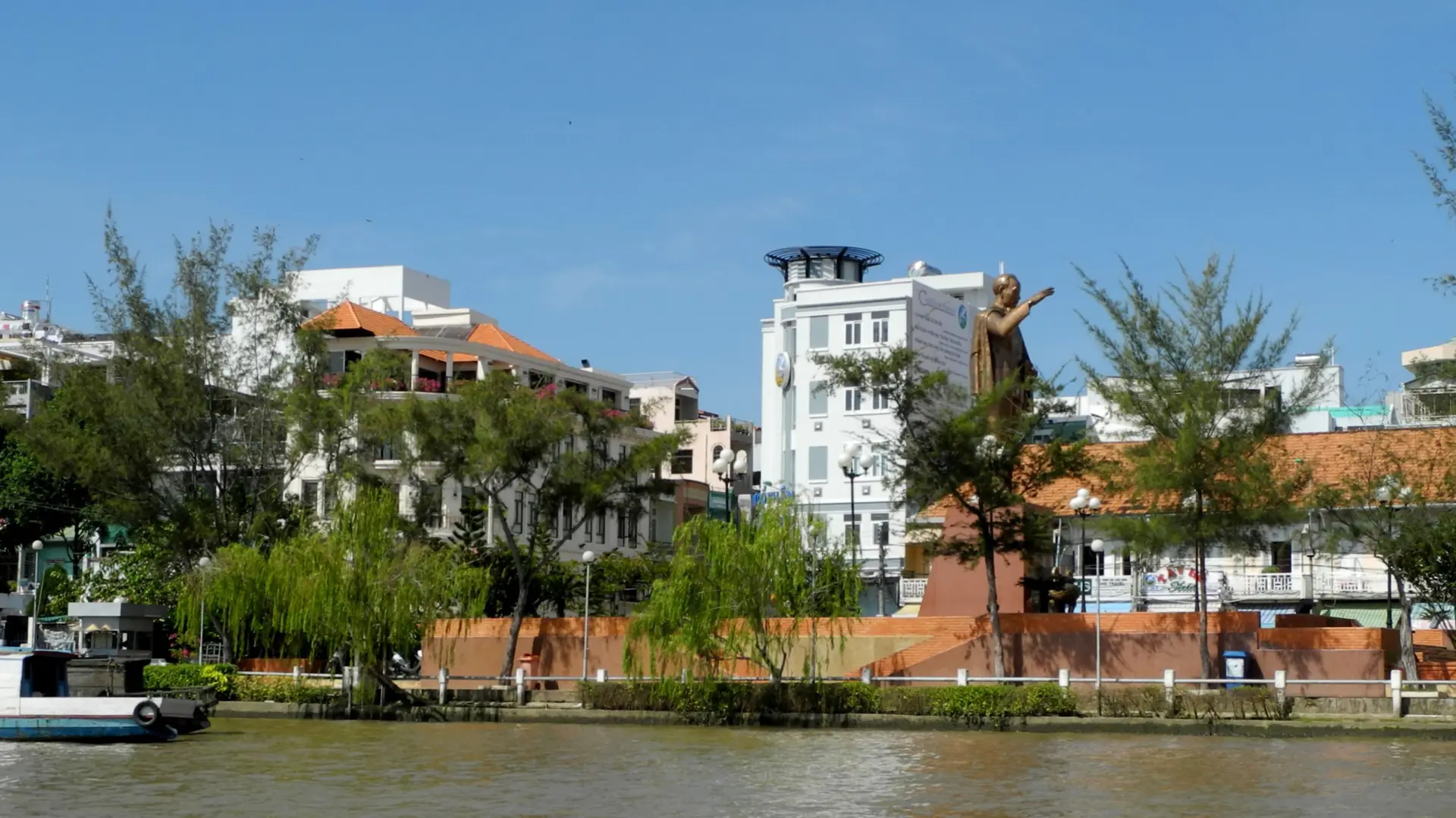 Can Tho riverfront buildings and memorial seen from a boat, a wider city scene
