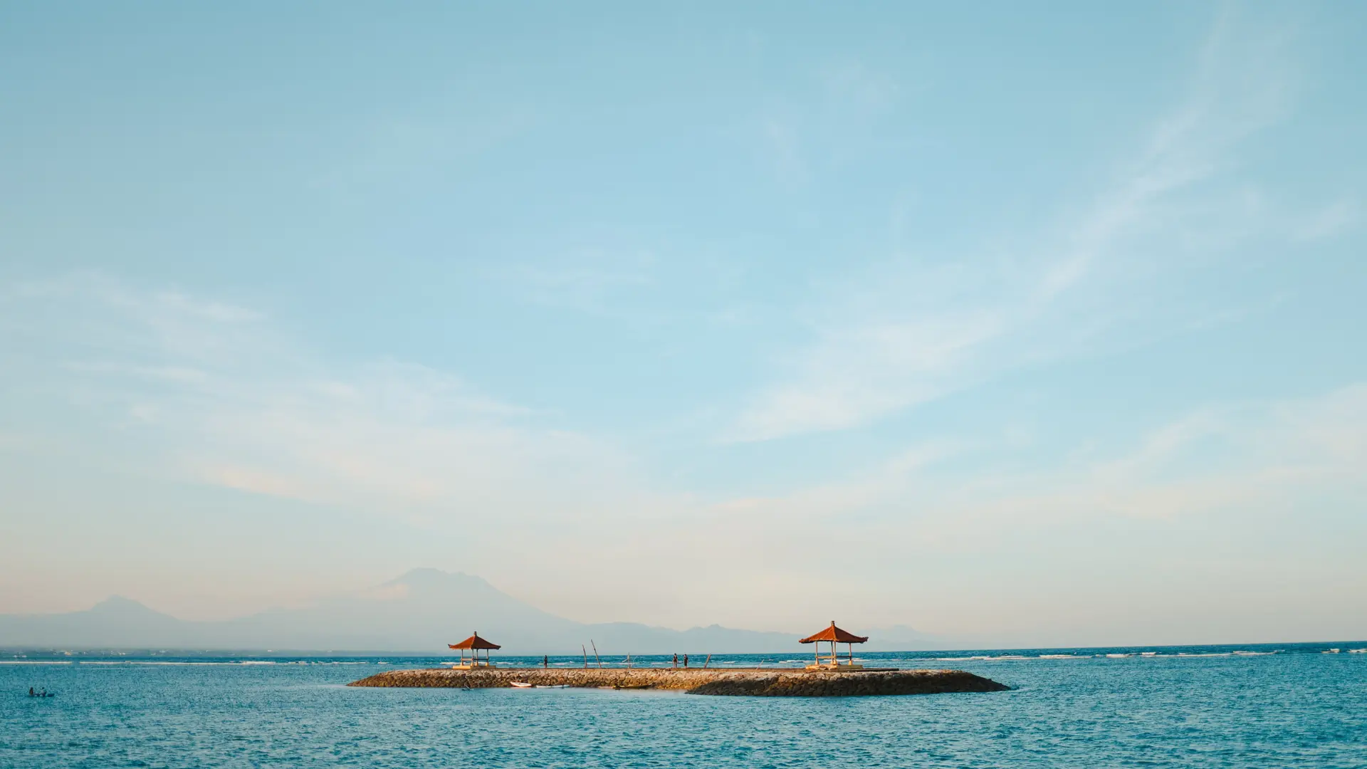 Two red-roofed pavilions beside turquoise water on Sanur’s coast