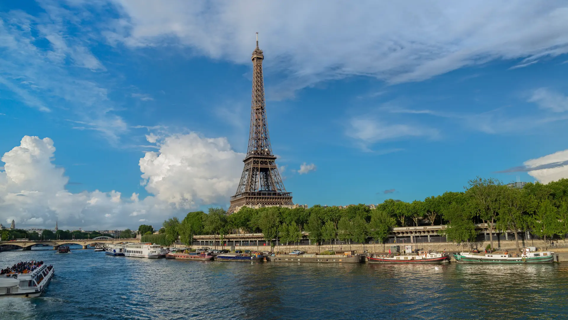 The Eiffel Tower and boats on the Seine under a blue Paris sky