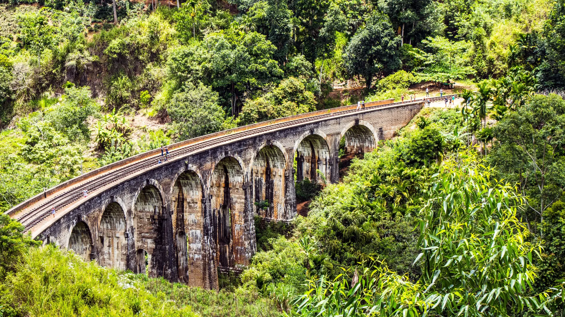 Nine Arches Bridge curving through green forest near Ella in daylight