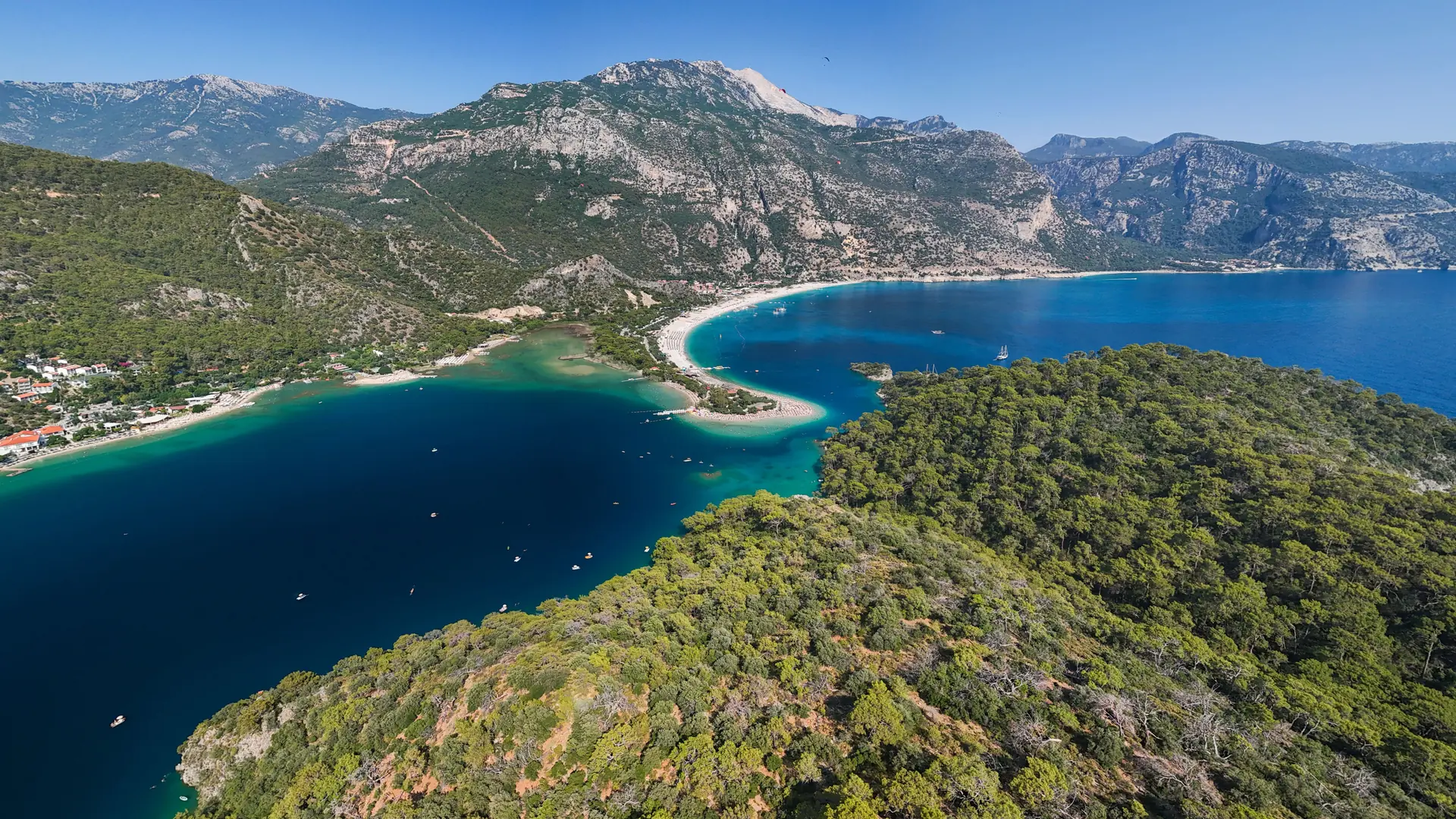 Ölüdeniz Blue Lagoon near Fethiye curving between turquoise water and forested mountains