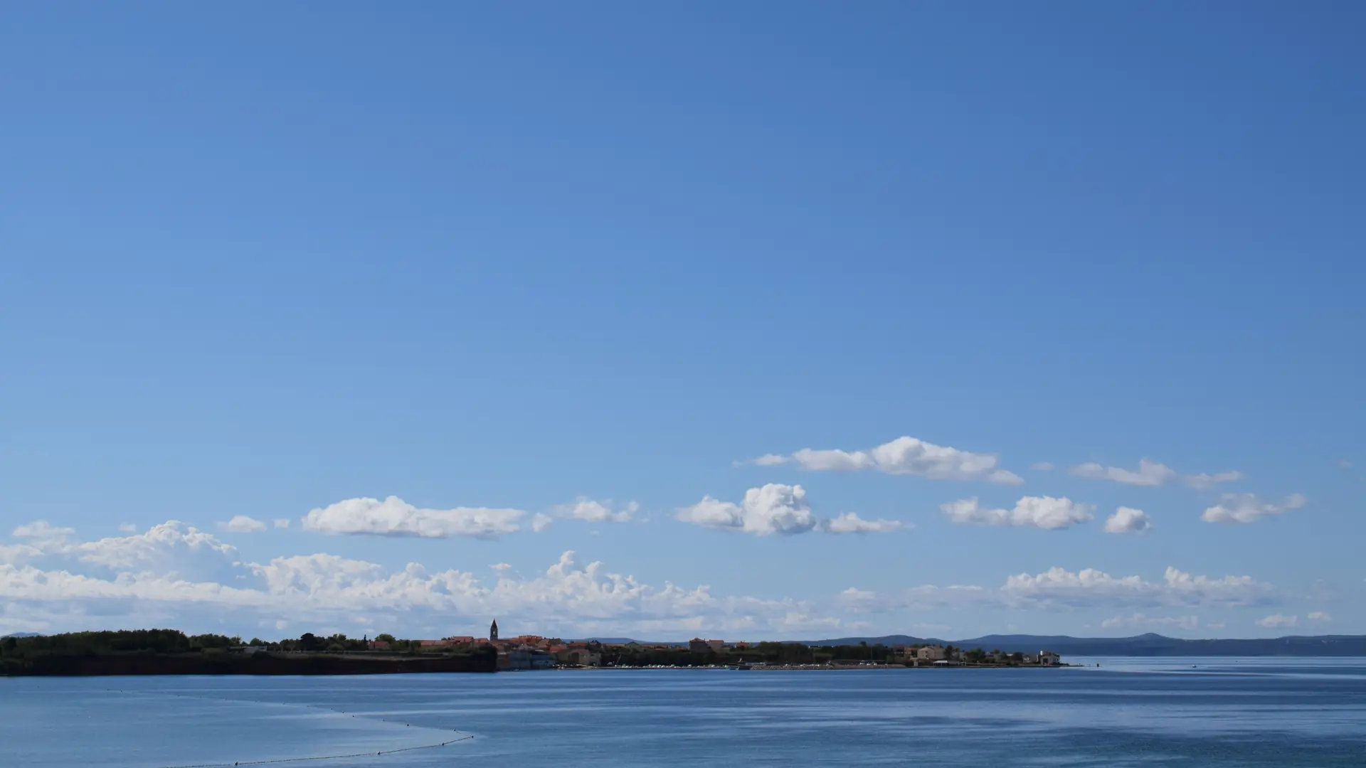 A calm bay with a small coastal settlement visible across the water near Zadar