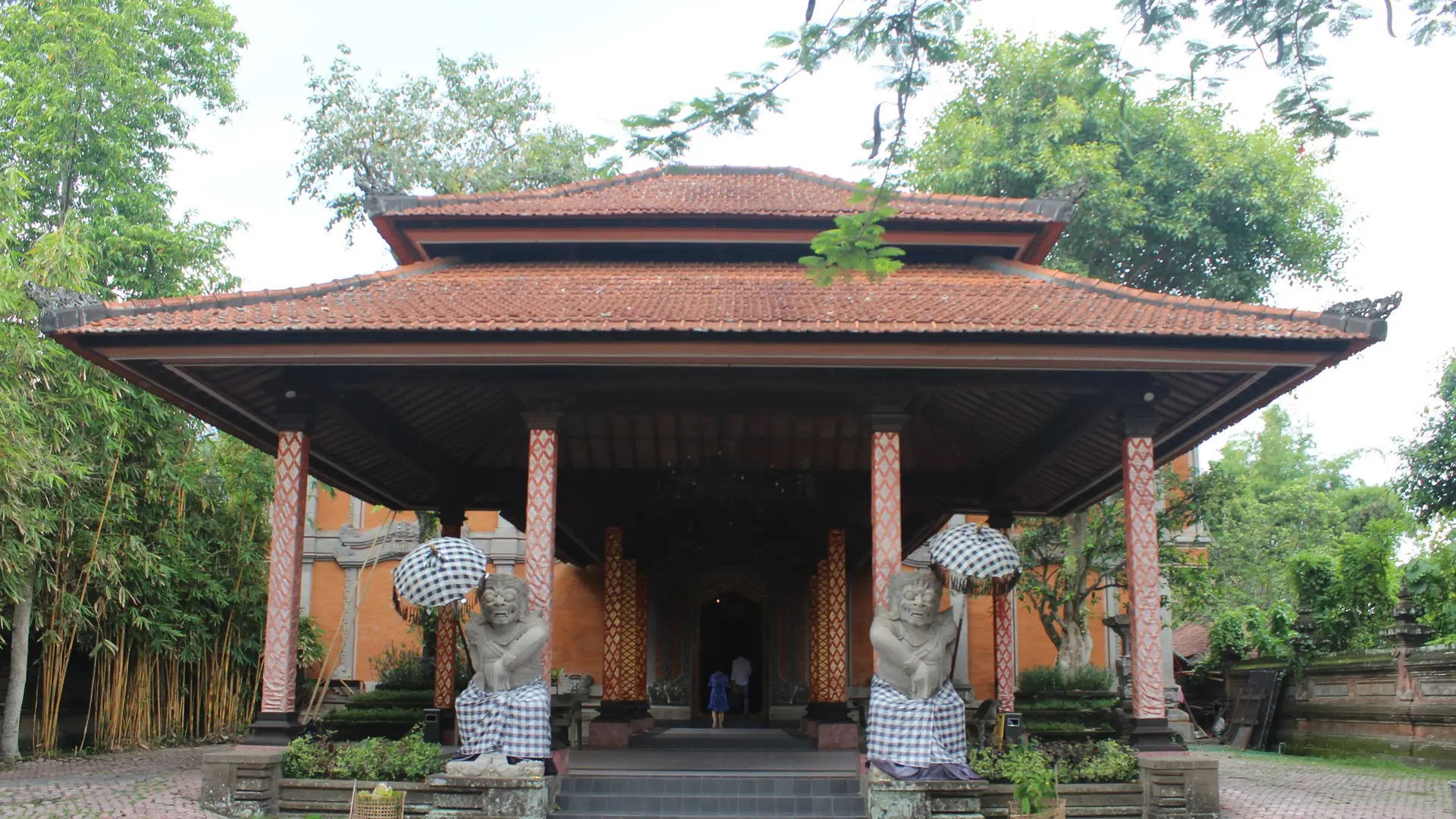 Red-roofed entrance pavilion and carved stone guardians at the Agung Rai Museum of Art in Pengosekan, Ubud