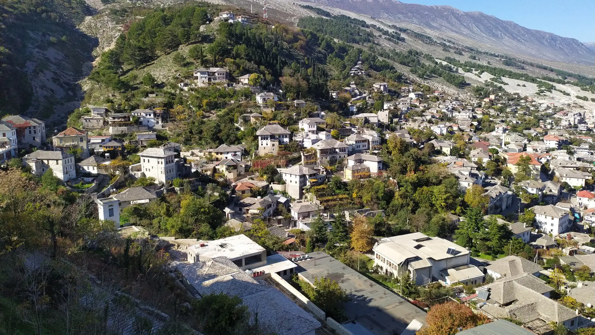 Gjirokastër's houses spreading across the hillside below the castle on a clear, sunny day