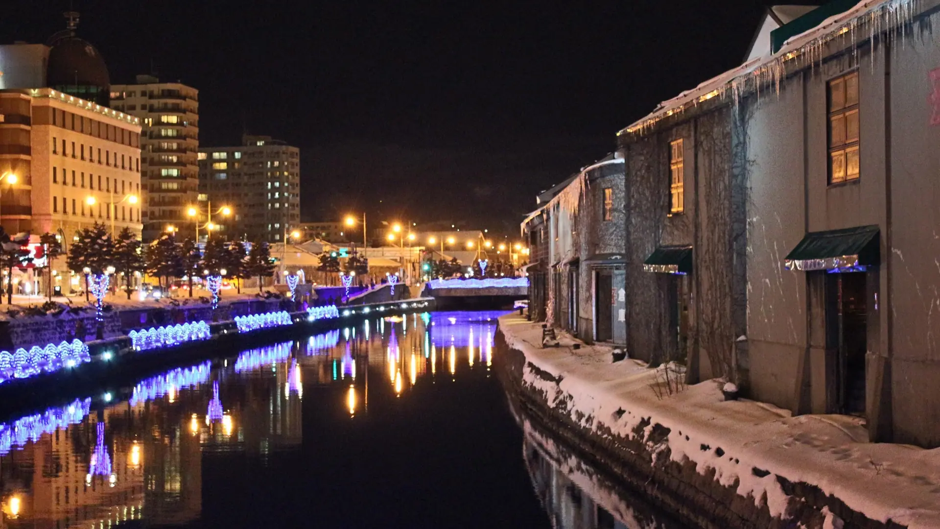 Historic warehouses reflected in Otaru Canal under winter snow