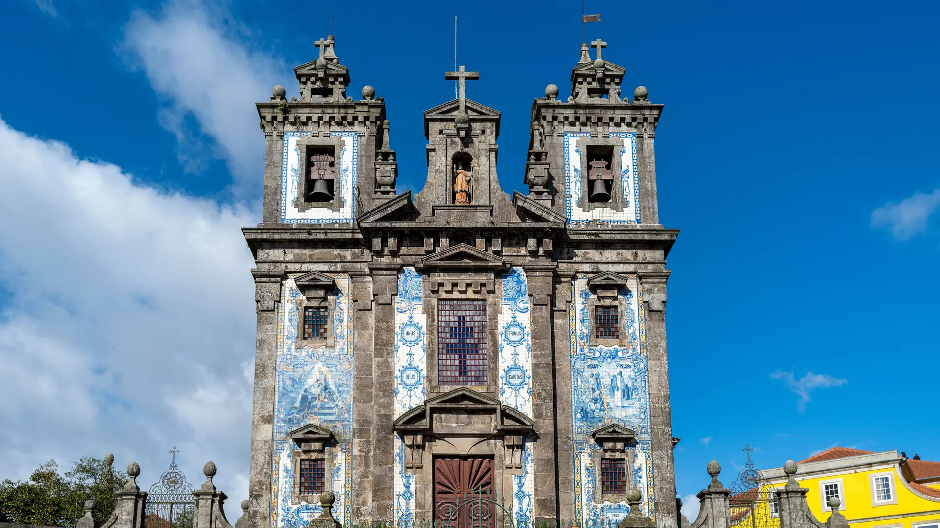 Blue-and-white tiles on Porto’s Santo Ildefonso church beneath a blue sky; wider city context