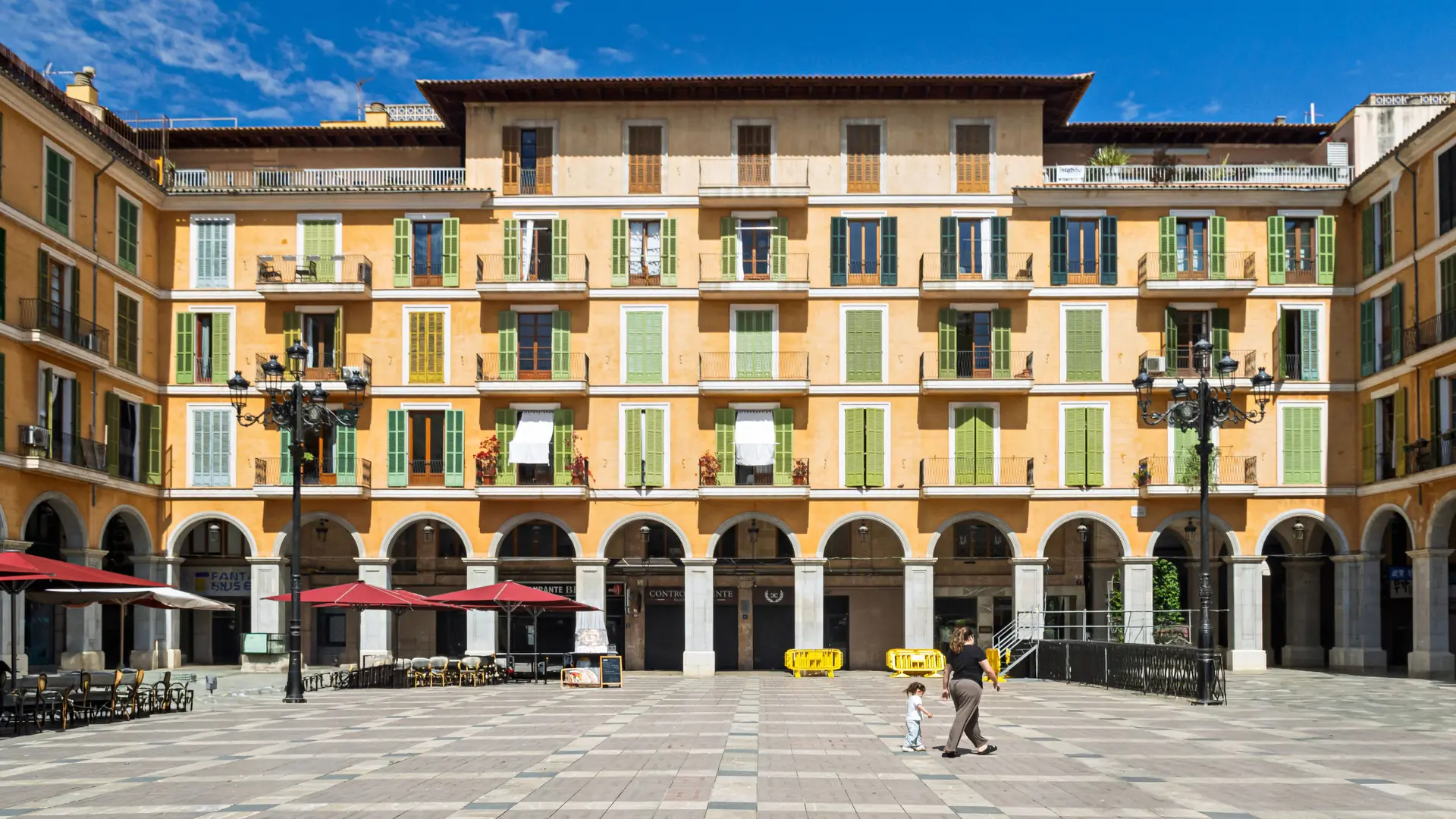 Sunlit yellow façades, green shutters and stone arcades around Plaça Major in central Palma