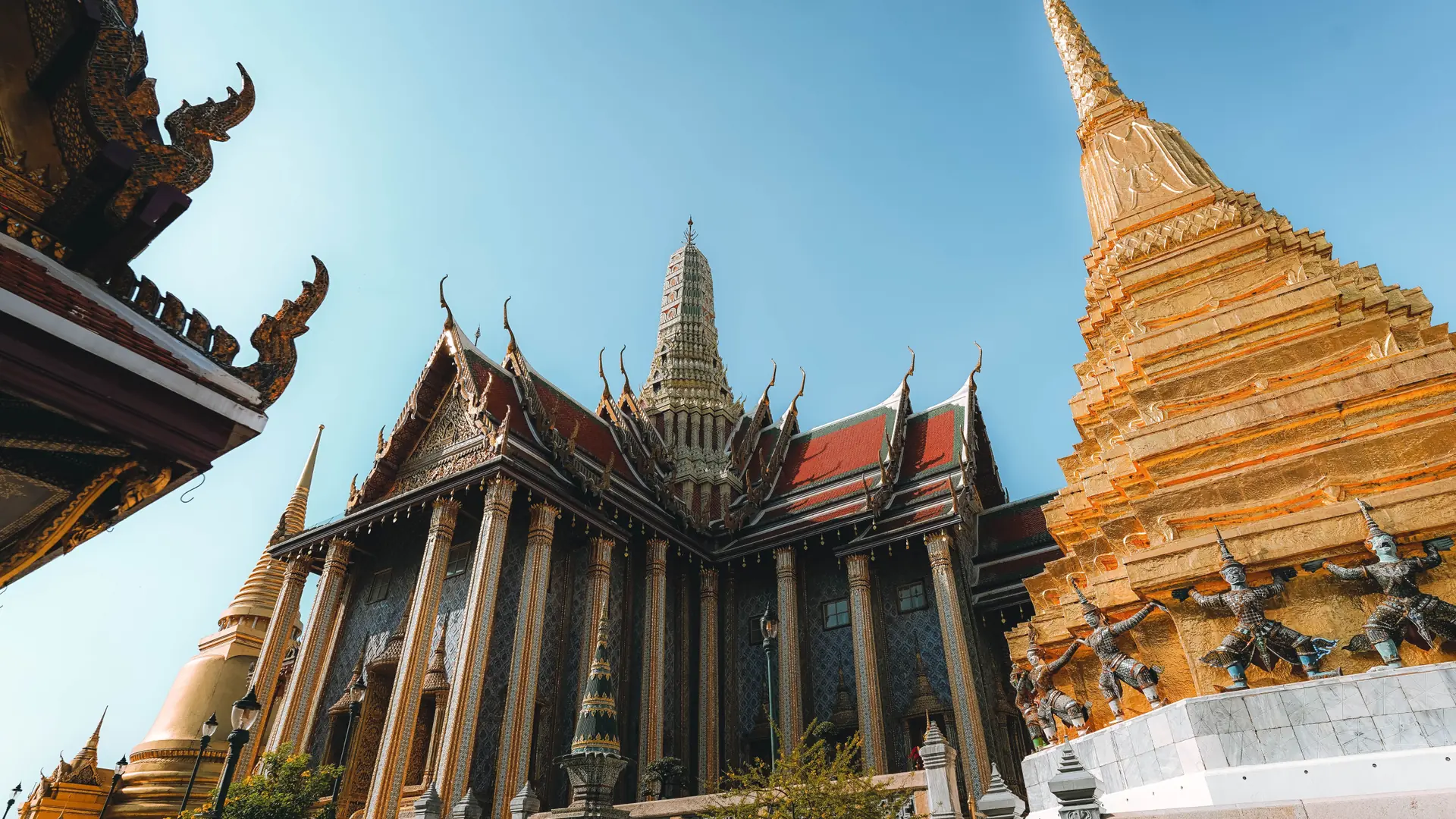 Sunlit golden chedi and ornate roofs at Bangkok’s Grand Palace, illustrating the wider city