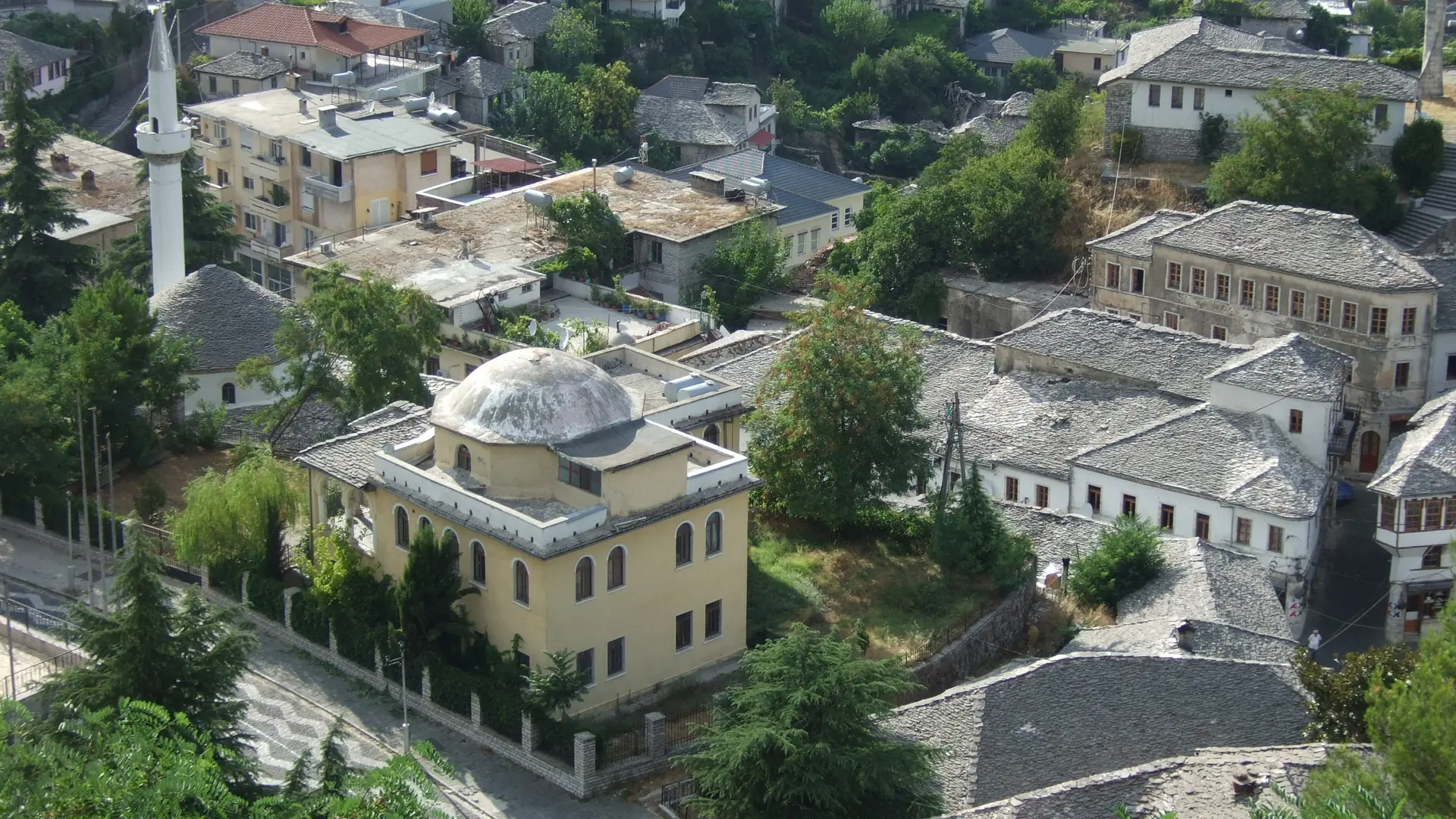 Stone-roofed houses around the Bazaar Mosque in Gjirokastër's old town on a sunny day