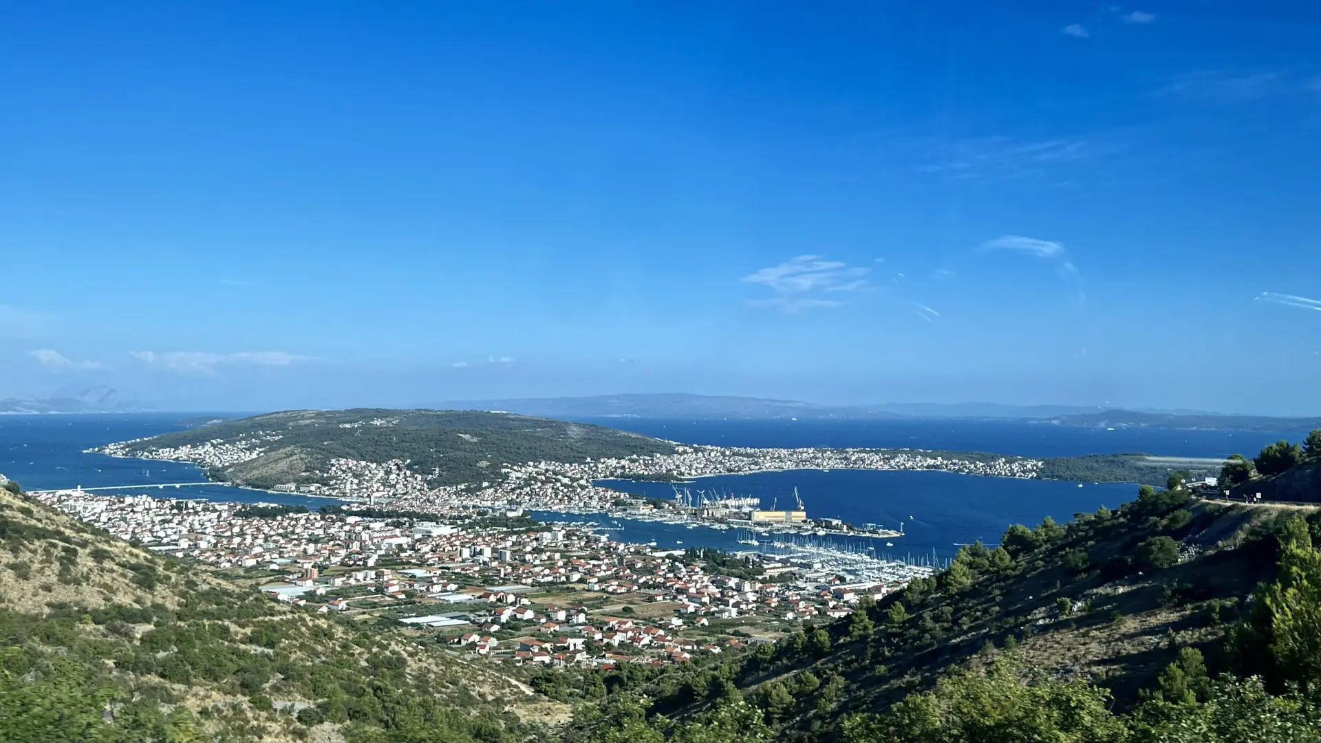 Seget Donji and Trogir below a hillside, with marinas and Čiovo across the water
