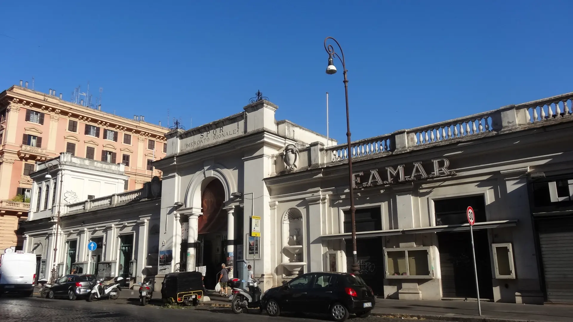 the cream-stone Mercato Rionale market building on a sunlit Prati street corner in Rome