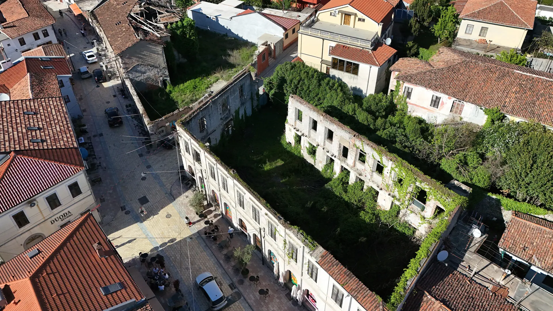 Tiled roofs and historic buildings along Gjuhadol Street in Shkodër, seen from above on a sunny day
