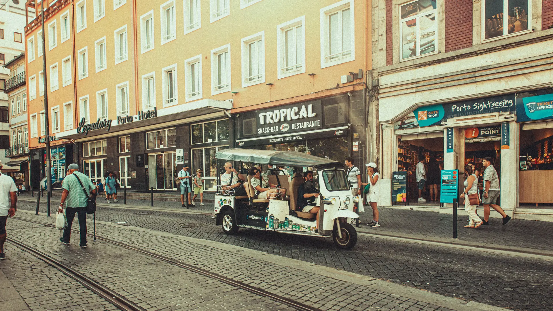 a sunny central Porto street with tram tracks and pastel-coloured façades