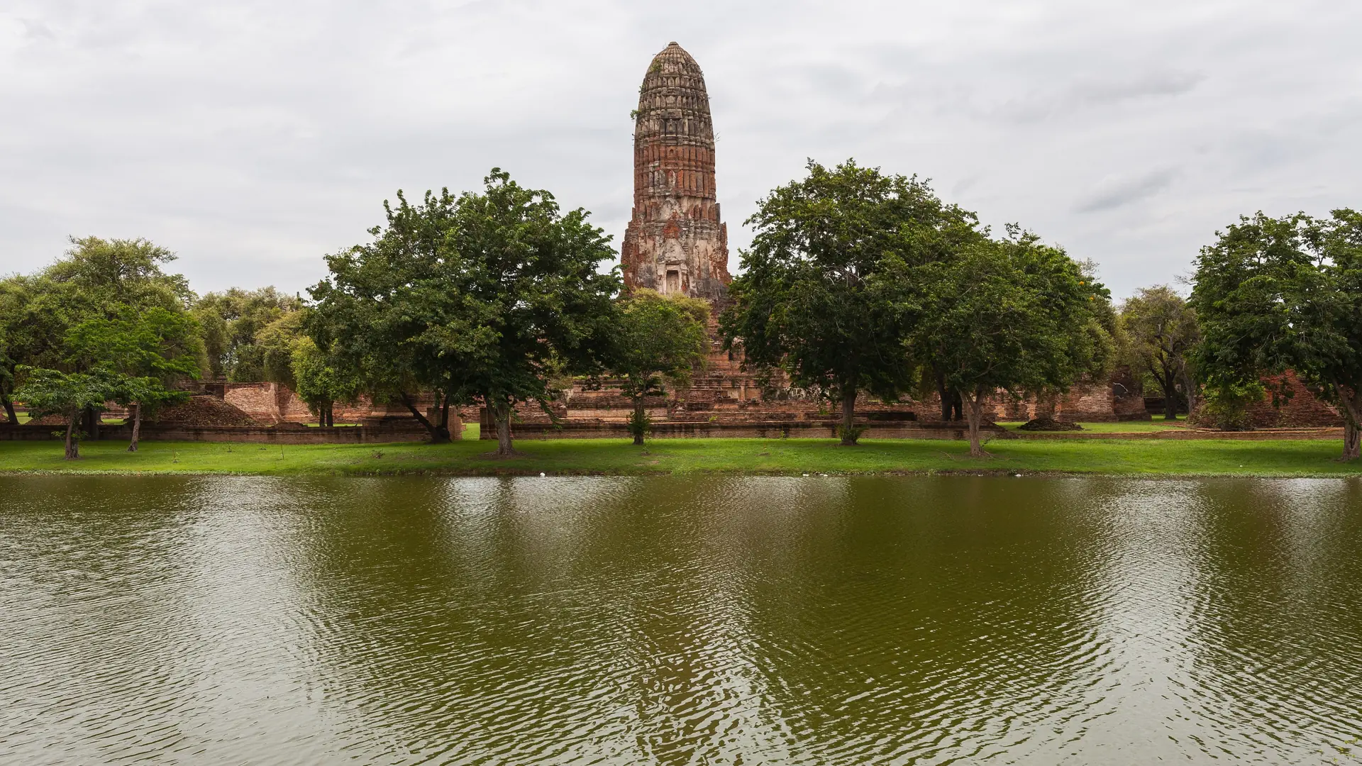Wat Phra Ram's tall prang rising beside trees and water
