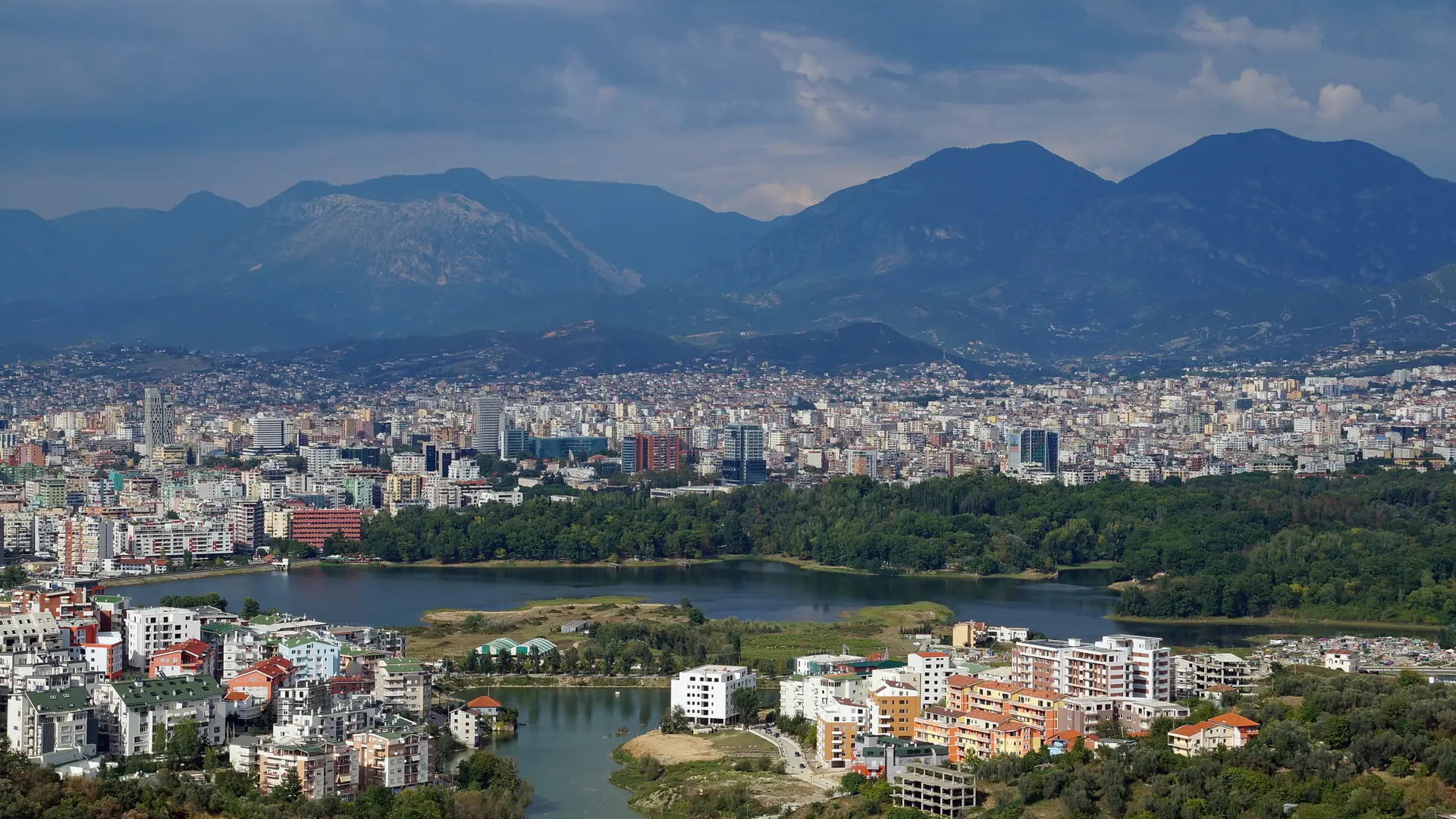 Tirana's Artificial Lake and Grand Park in front of the city, with mountains behind on a clear day