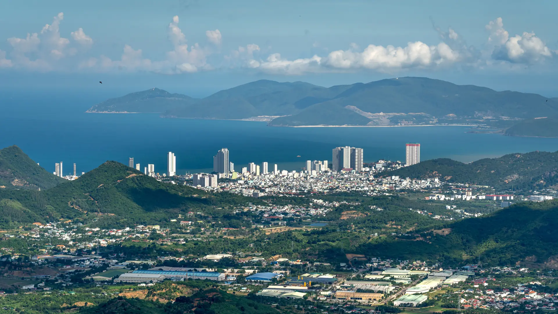 Sunlit Nha Trang city and bay with hills across the water