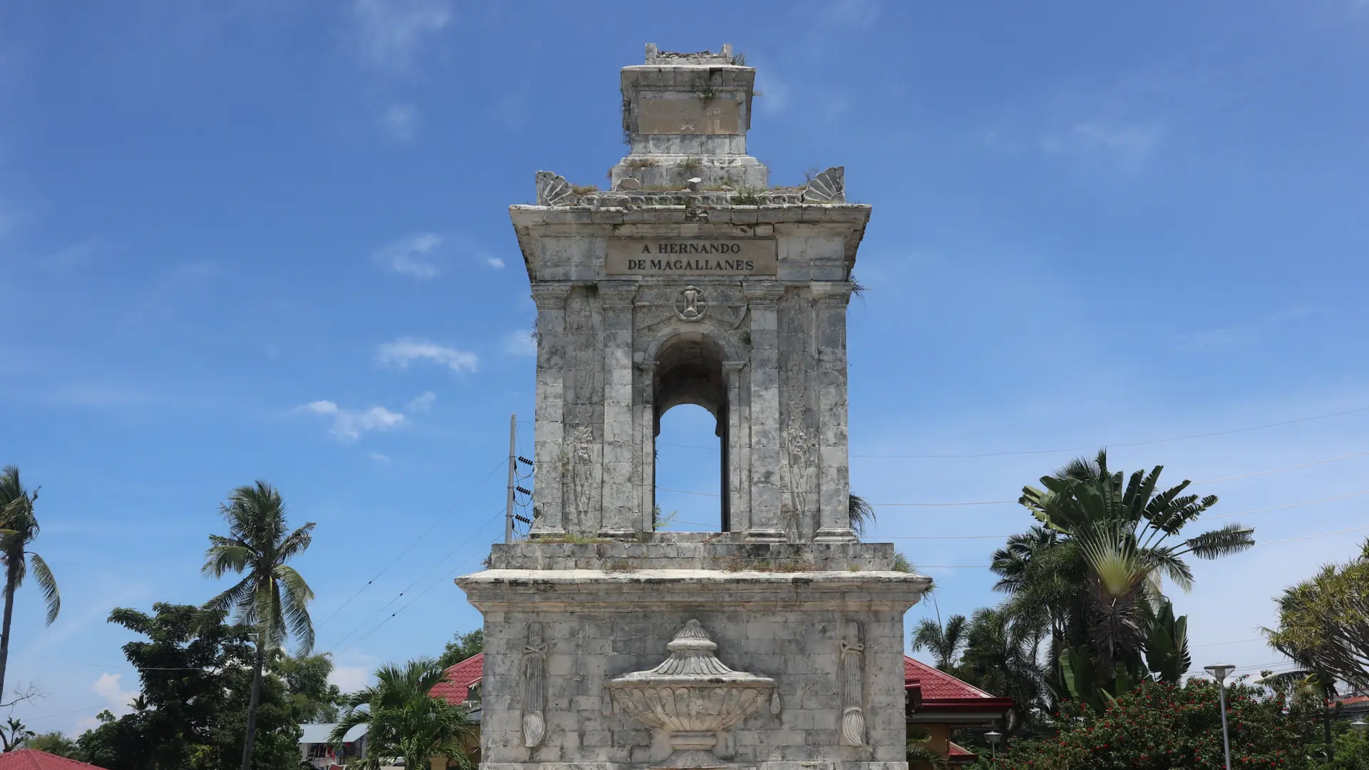 Magellan monument and palm trees at Mactan Shrine in Lapu-Lapu City under a blue sky