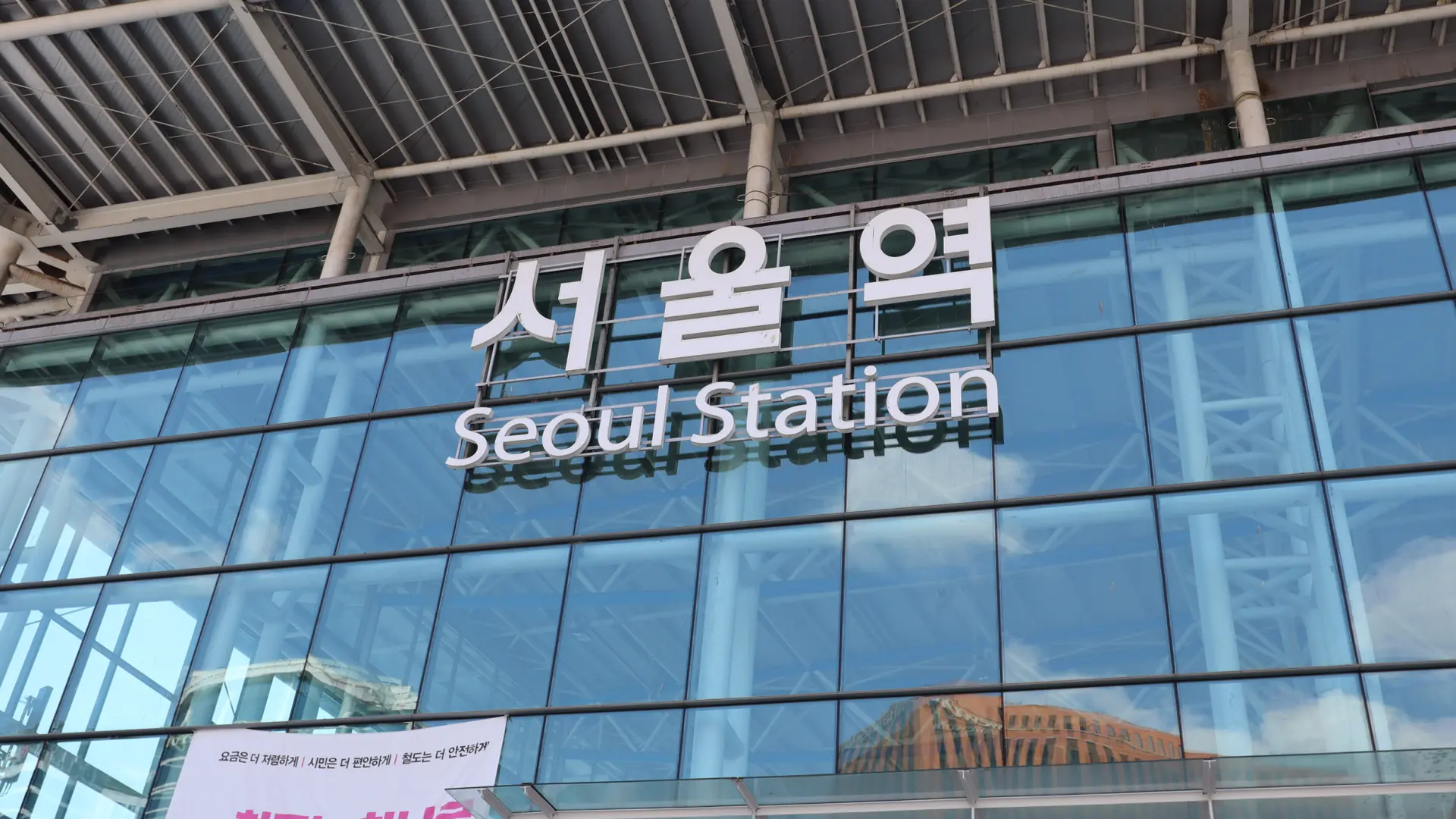 Seoul Station name in Korean and English on its blue glass facade in daylight