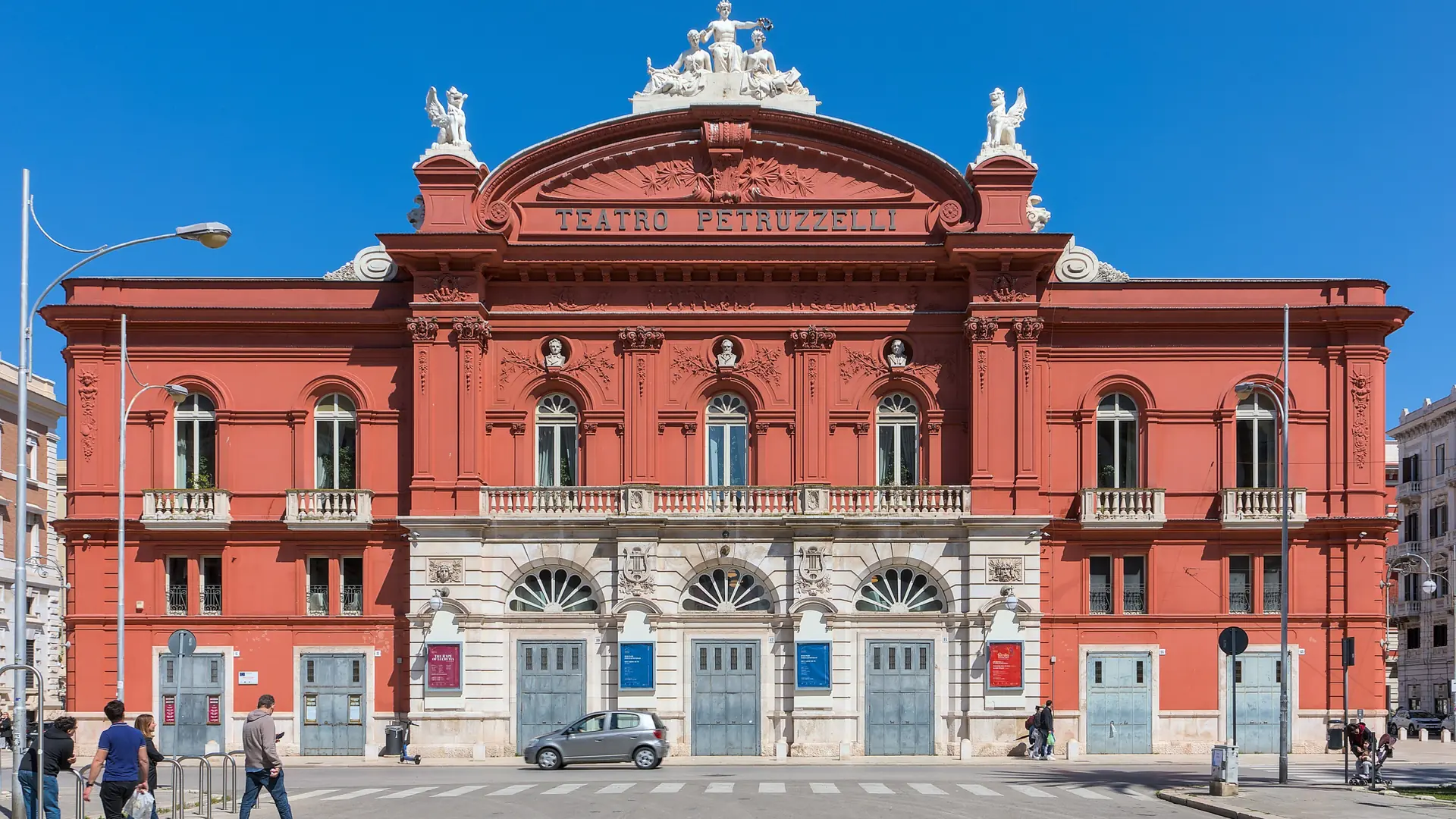 The red facade and pale sculptural details of Teatro Petruzzelli in Bari.