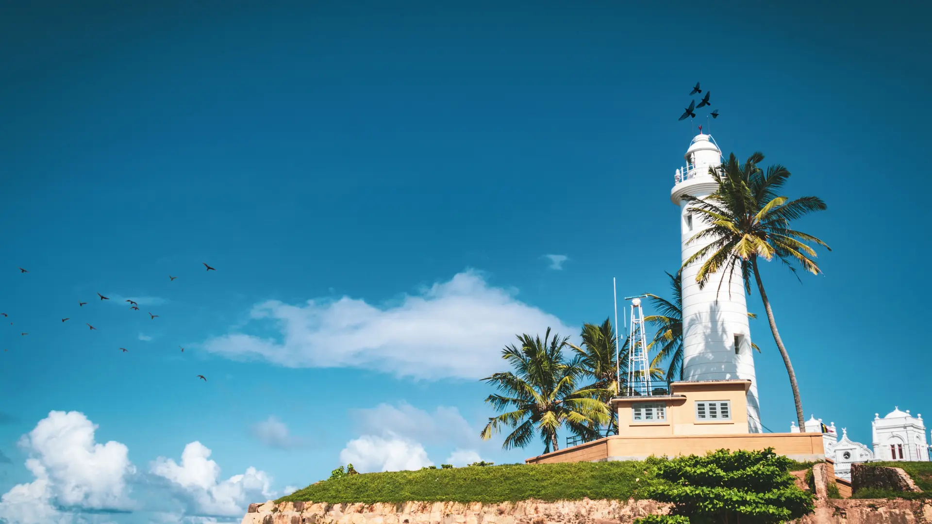 White Galle Lighthouse above fort ramparts beneath a clear blue sky