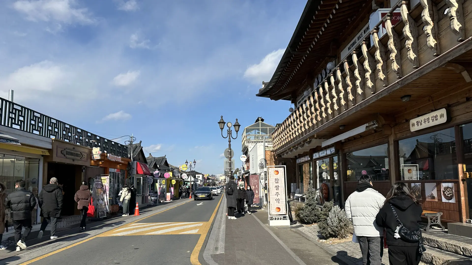 A sunny Hwangnidan-gil street in Gyeongju with a Hwangnam gimbap shopfront and pedestrians