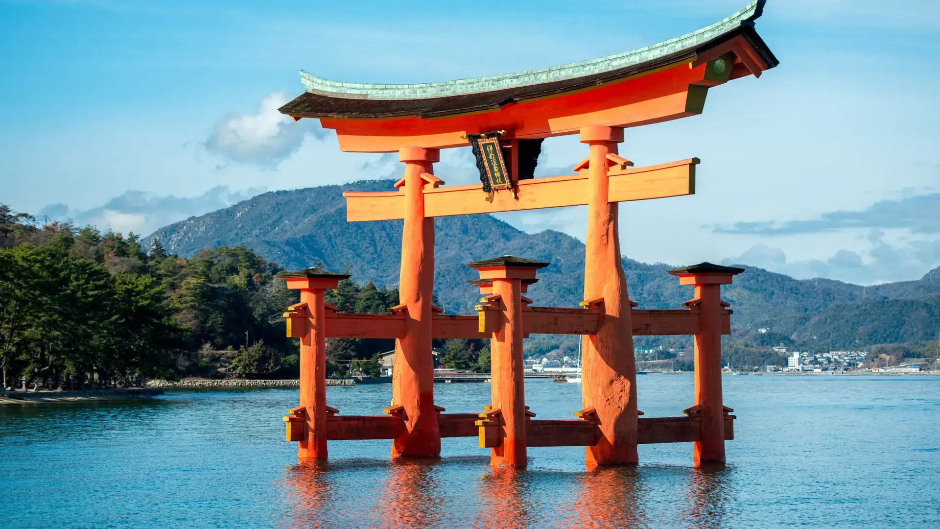 Itsukushima Shrine's vermilion torii standing in blue water off Miyajima