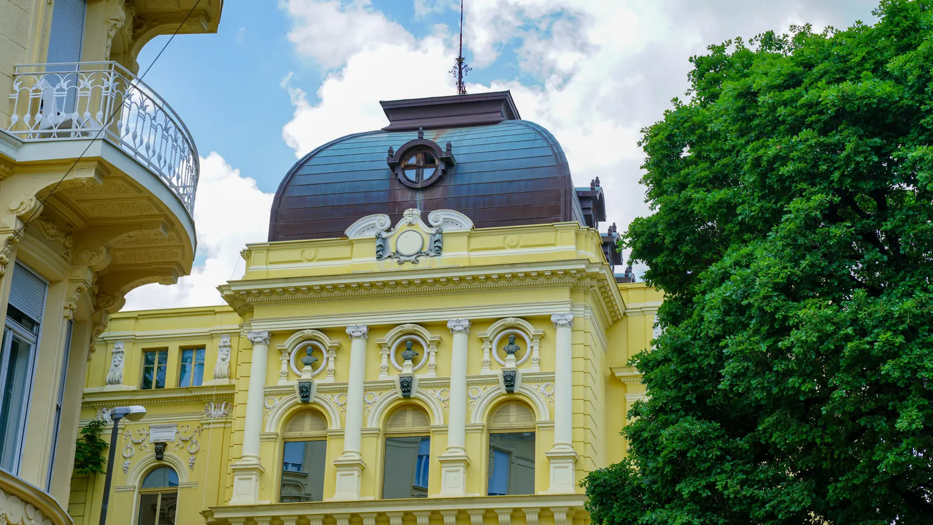 An ornate yellow historic building in central Opatija, with balconies and a curved roof