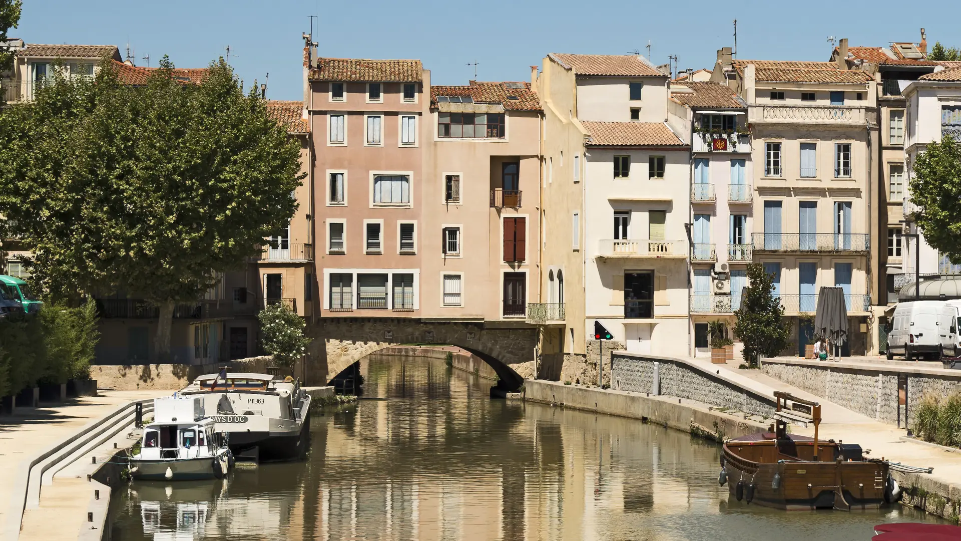 The Pont des Marchands and sunlit buildings above the Canal de la Robine in Narbonne