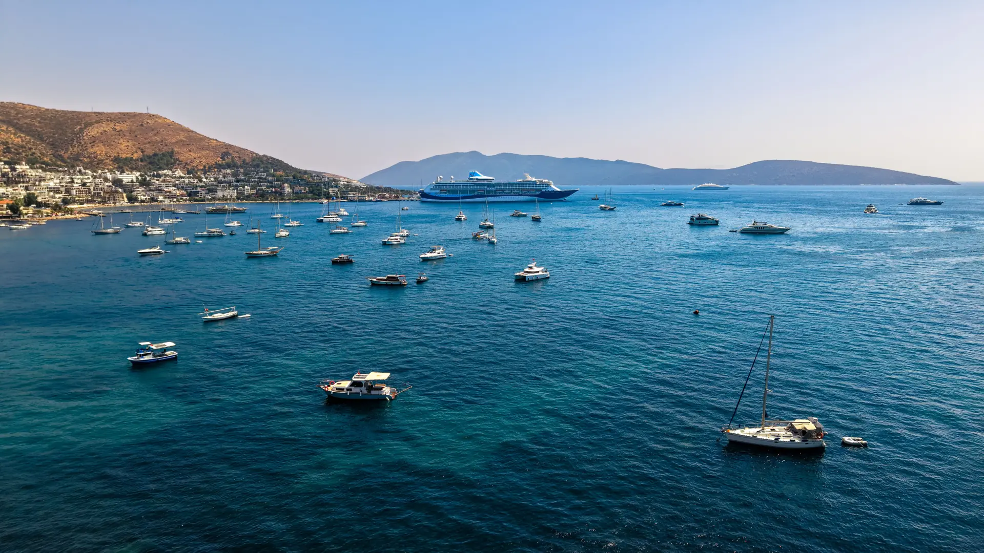 A quiet Bodrum Peninsula bay with sailing boats and low white houses beside blue water