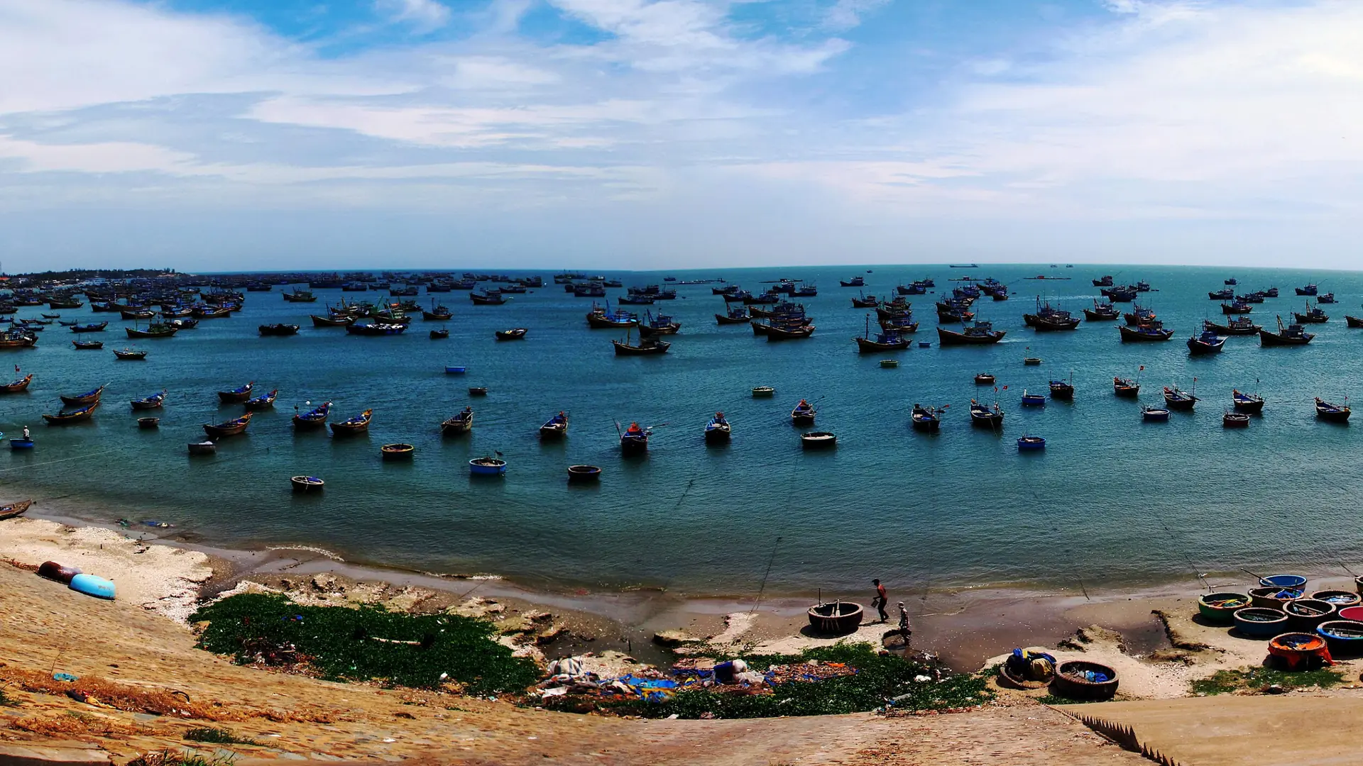Colourful boats and basket boats in the sunlit fishing harbour near Mui Ne village