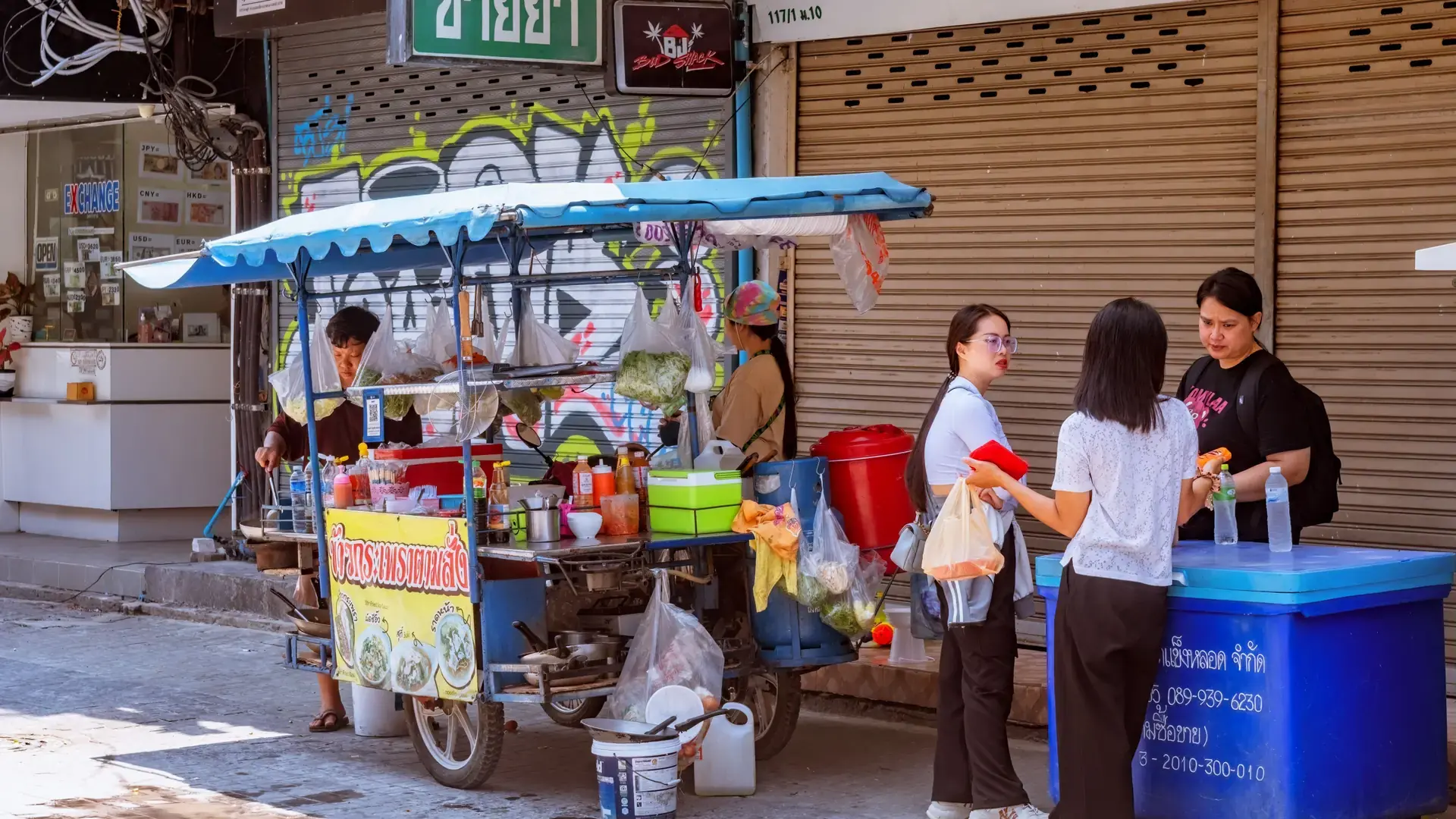 A street-food vendor serving customers at a daytime Pattaya stall