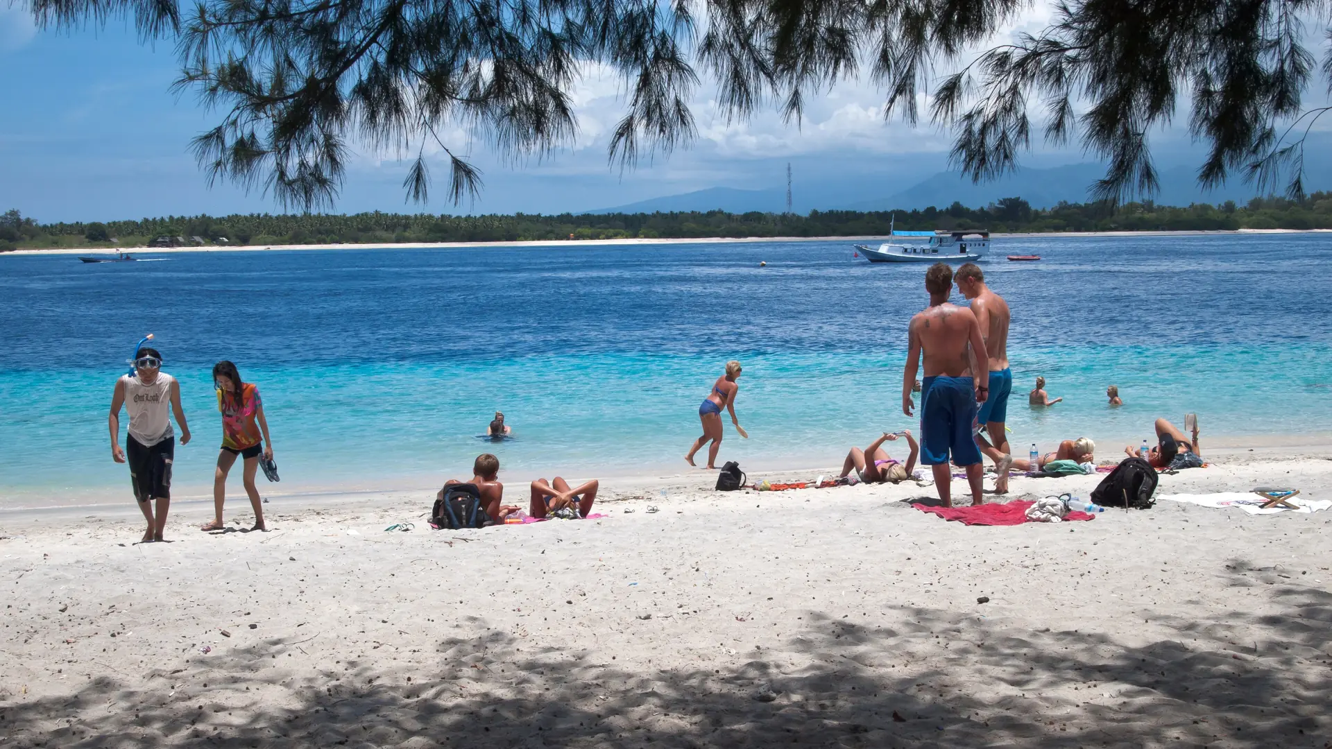 Travellers on Gili Trawangan’s white sandy shore beside turquoise water