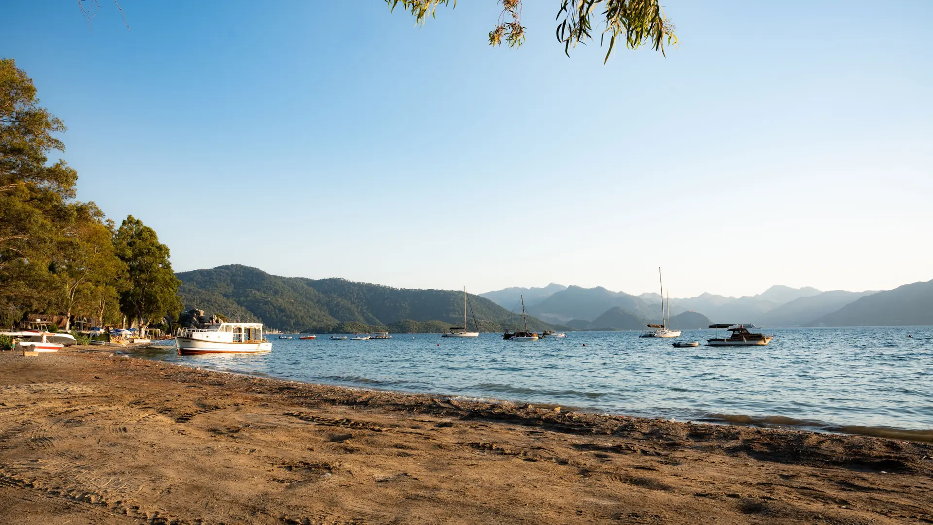 A quiet Marmaris beach with boats, forested mountains and calm blue water